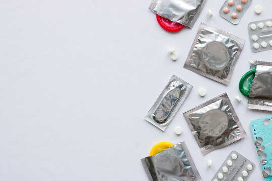 birth control pills and condoms on a white background with space