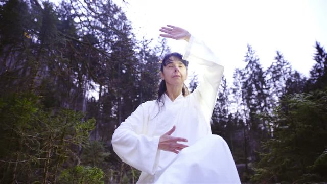 Woman make Nu Dan Gong forms while sitting in nature 4K
