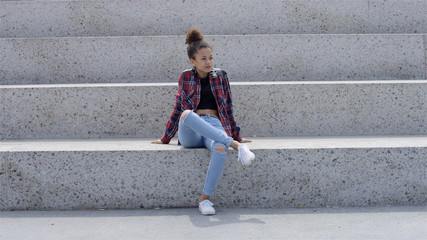 Fototapeta na wymiar Beautiful young african american woman relaxing in urban background.