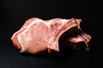 Top view raw pork chop steak and garlic, pepper, salt on wooden background.