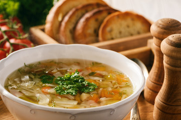 Vegetable soup with bread on wooden tray.