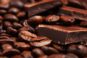 Broken chocolate bar and spices on wooden table.