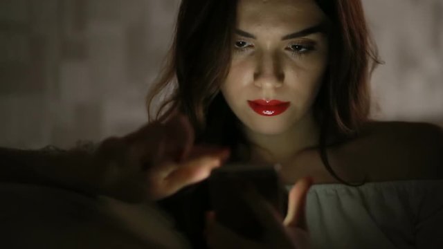 woman with a telephone in the dark at home on the couch. phone reflection face