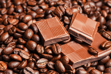 Broken chocolate bar and spices on wooden table.