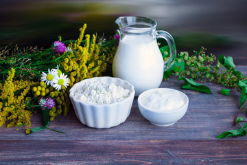 Concept of natural products and healthy eating - field flowers and organic dairy products on wooden table - summer rural symbol