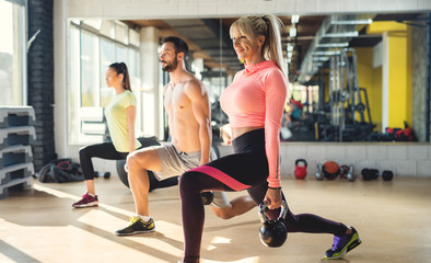 Obraz na płótnie Canvas Healthy athletes exercise with kettlebells at fitness studio. 