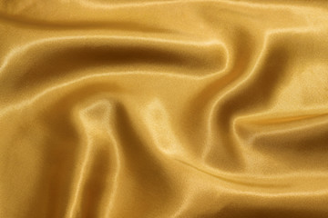 Smooth golden satin or silk background. The texture of the fabric.