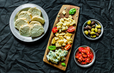 Flat lay of Italian cheese antipasti delicatessen platter against black background.