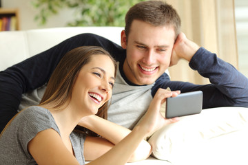 Happy couple watching videos in a phone