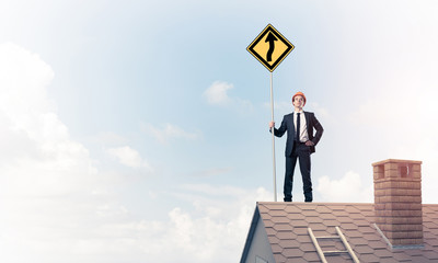 Engineer man on brick roof with sign in hands. Mixed media