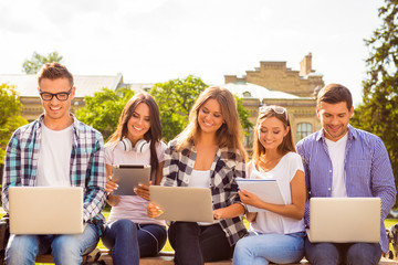 five happy smiling diverse students sitting on bench and study u
