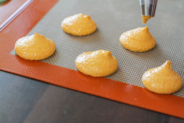 Piping out yellow macaron mixture on to the baking tray