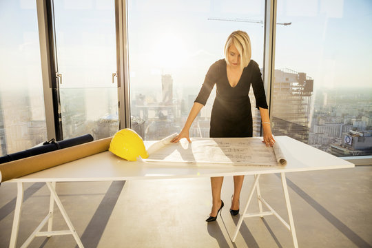 Businesswoman in office examining blueprint