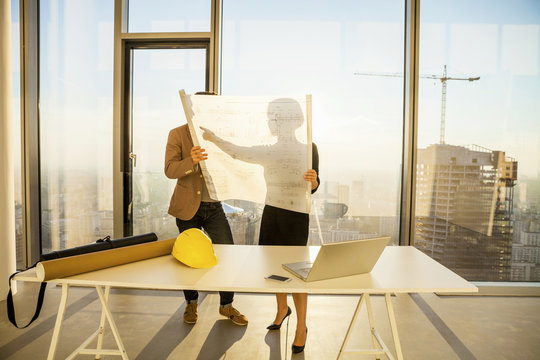 Two architects in office examining blueprint