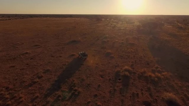 Aerial view hunters traveling in a car at sunset in search of prey