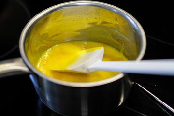 Yellow sauce in the sause pan with the white spatula