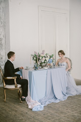 Obraz premium The newly-married couple sitting at the wedding centerpieces. Bridal fashion.