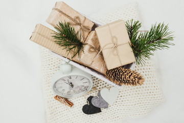 The Valentines day concept. Valentines gifts. Present gifts boxes piled in a white wicker basket on a snow background. Hearts made of wool, watches, cinnamon lie on a woolen blanket. Top view.