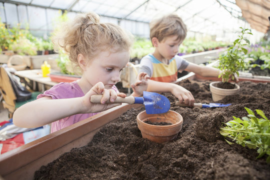 Two children in greenhouse planting plants