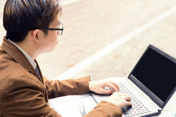 man is using computer laptop for working at outdoor in public park.