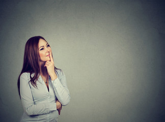 happy woman thinking with hand on chin looking up