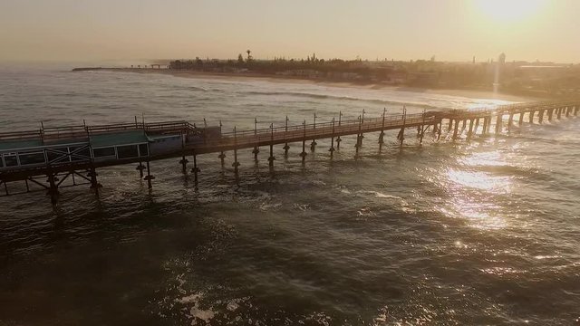Aerial view pier stretching into the ocean at sunset