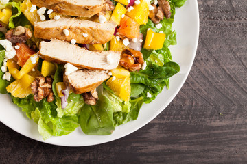 Orange Walnut Chicken Salad  on a white plate with  dark wooden background with feta cheese