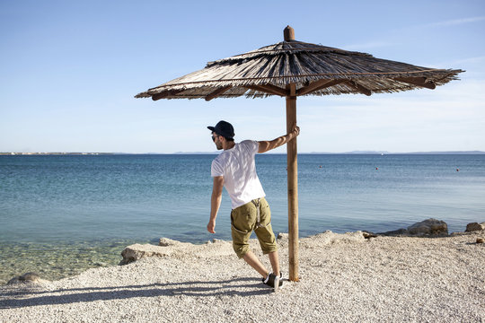 Young man standing under parasol on beach