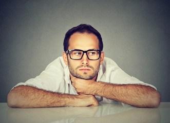 Bored man daydreaming showing no interest sitting at table