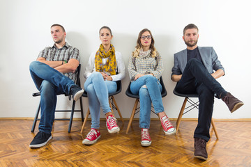 Group of young people is sitting in a row in an office lobby and waiting for the job interview.