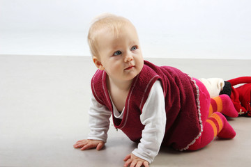 Naklejka premium Adorable baby girl in red dress playing. .
