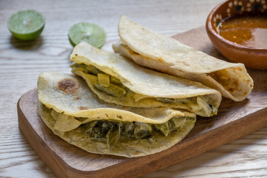 Authentic Mexican poblano pepper tacos on a wooden board with lime and salsa