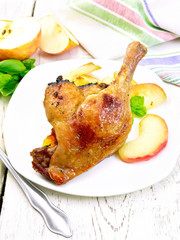 Duck leg with apple in plate on light board