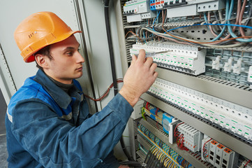 electrician works with electric meter tester in fuse box