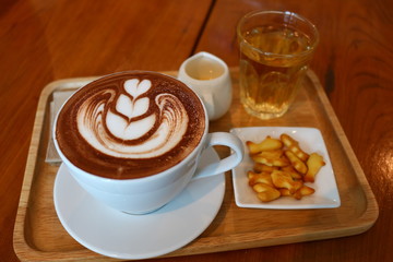 Nice latte art on the cup of hot chocolate with syrup and biscuits