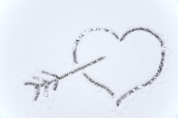 drawing heart and arrow on white snow background