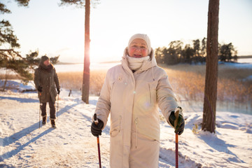 Winter sport in Finland - nordic walking. Senior woman and man hiking in cold forest. Active people...