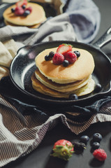Home made pancakes with berries on metal frying pan decorated wi