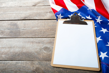 Fototapeta na wymiar blank clip board and USA flag on wooden background