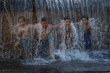 Asian boy playing at waterfall