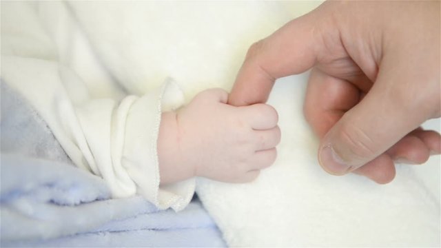 Father holds newborn infant baby's hand for the first time.