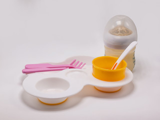 Containers such as baby bottles, rice dishes, cutlery and glasses in white background.