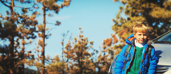 little boy with backpack travel by car in nature