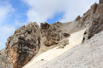 People climbing the Via Ferrata Severino Casara and snow field in Sexten Dolomites mountains, South Tyrol, Italy