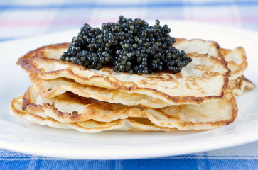 Pancakes with black caviar on plate