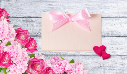 Pink roses and hydrangeas with two hearts and greeting card on b