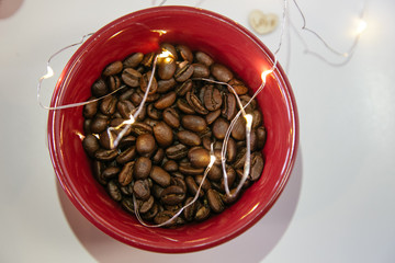 Coffee beans in a red cup with warm white lights. Valentine's day