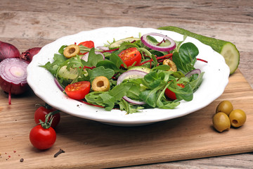 Frischer Salat mit Zwiebeln, Käse, Tomaten und Gurken aus Holzplatte