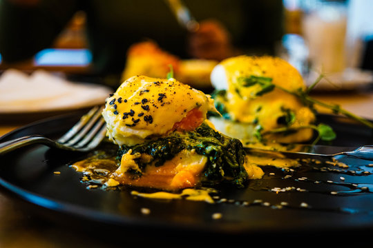 Eggs Florentine close up on a black plate with a fork also in sh