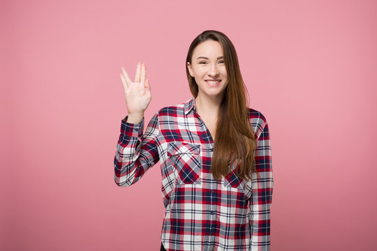 hipster girl showing spock gesture over pink background isolated